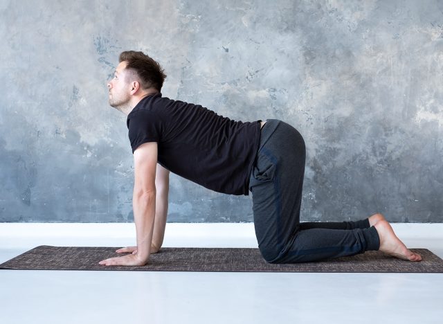 Young yogi men practices yoga asana bitilasana or cat cow pose in urban studio.