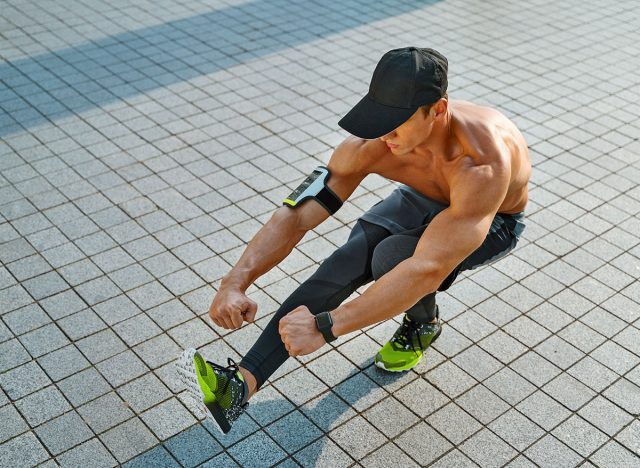 Sporty man doing squat on one leg. Photo of young man workout along outdoor in the city. Pistol Squats. 