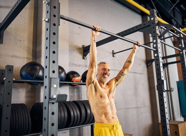 Cheerful athlete grabbing the chin-up bar with both hands before performing the dead hang exercise