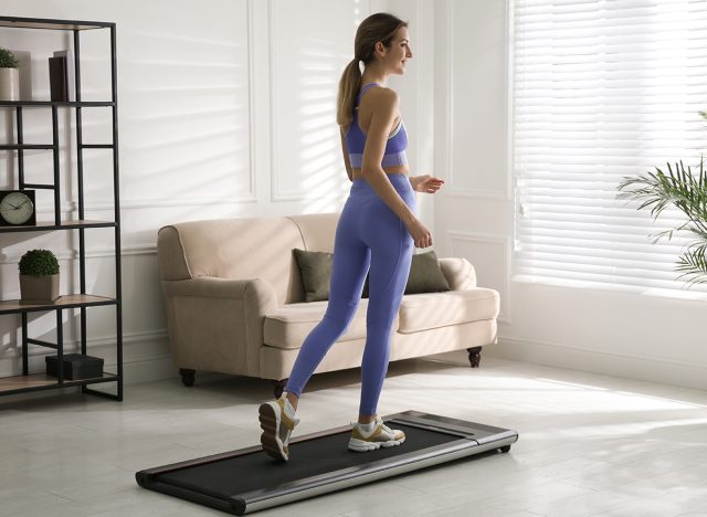 Sporty woman training on walking treadmill at home