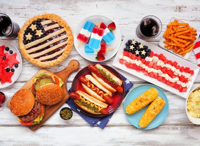 Fourth of July, patriotic, American themed food. Overhead view table scene on a white wood background.