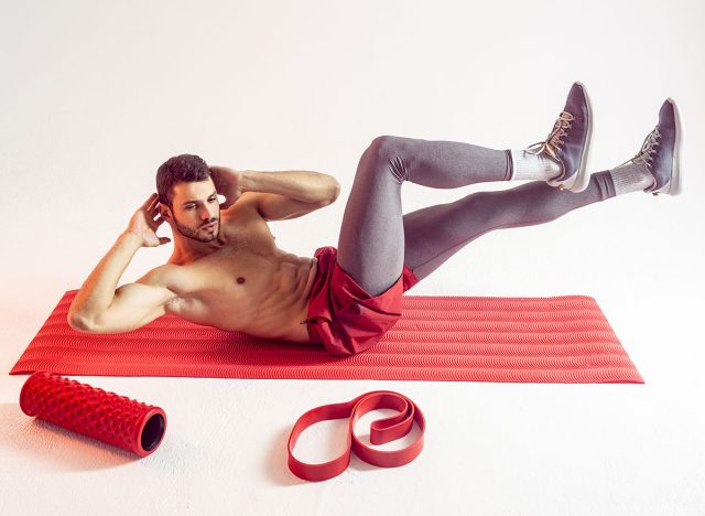 Sportsman train abdominal muscles on fitness mat