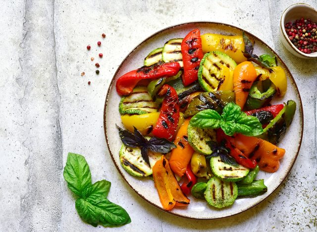 Grilled colorful vegetable : bell pepper, zucchini, eggplant on a plate over light grey slate, stone or concrete background. Top view with copy space.