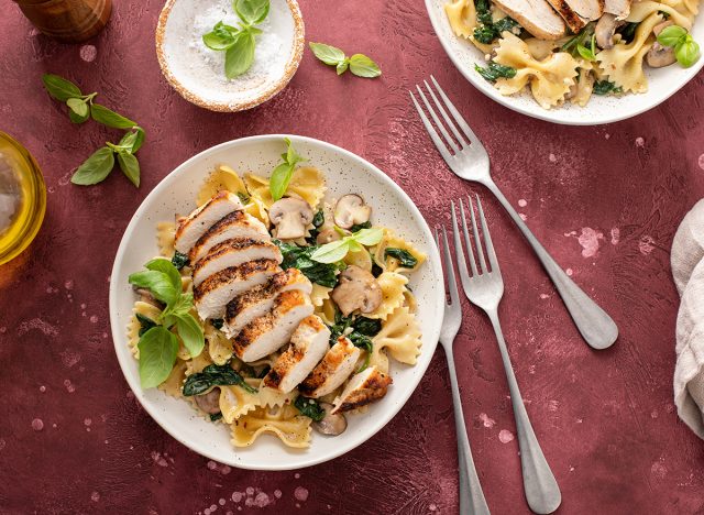 Grilled chicken served with mushroom and spinach pasta and fresh basil