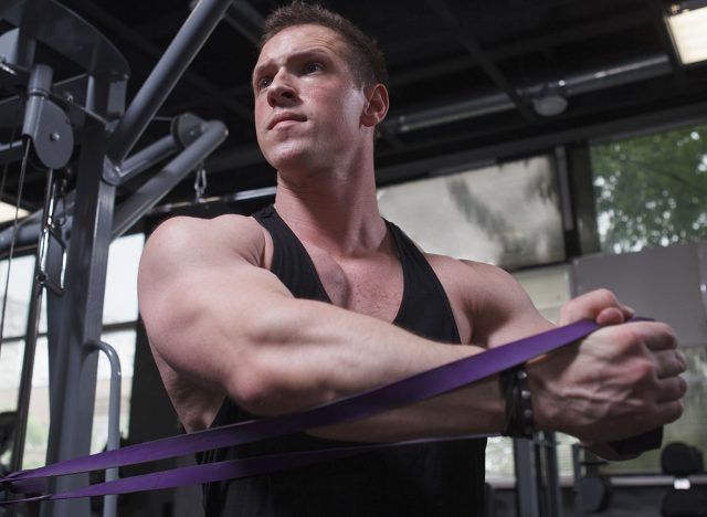 Vertical shot of a muscular sportsman doing core twists with resistance band