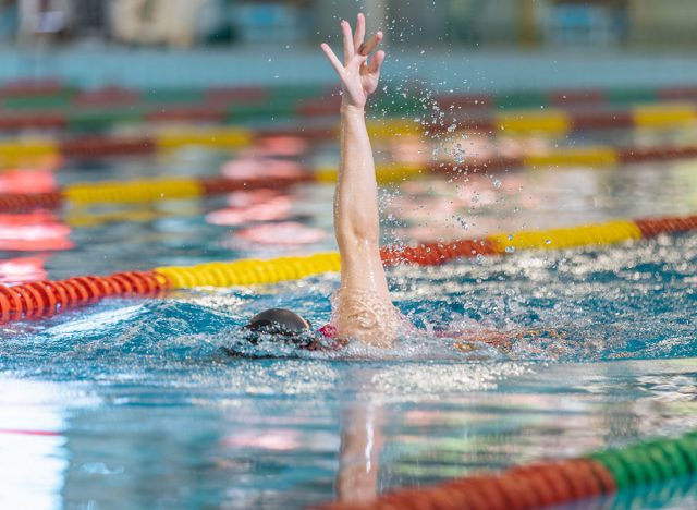 Professional female athlete swimming backstroke in the pool, arms movement. Competitive swimming drills concept.