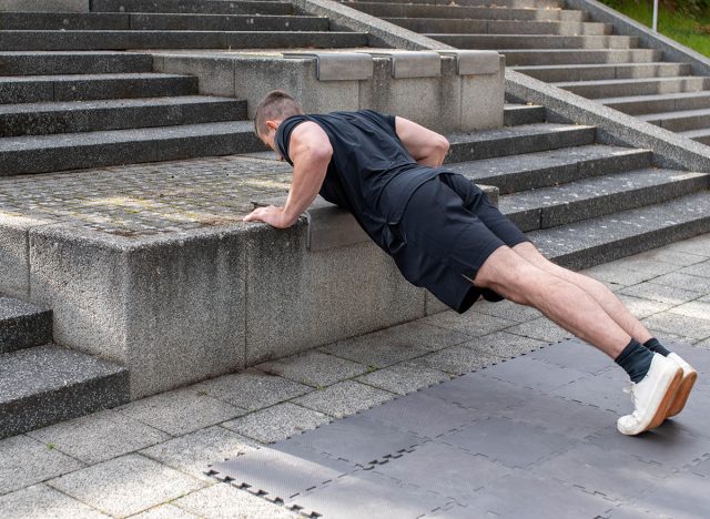 Incline push-up doing by a young athletic man. Push-up modification for beginners