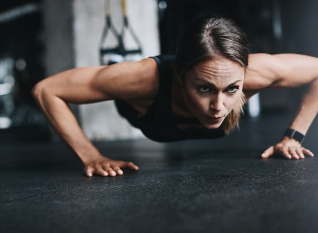 Push ups, girl and fitness in gym on ground for workout, health and wellness with power or resilience. Plank, athlete and training in sports club for exercise, competition and body goals with muscle