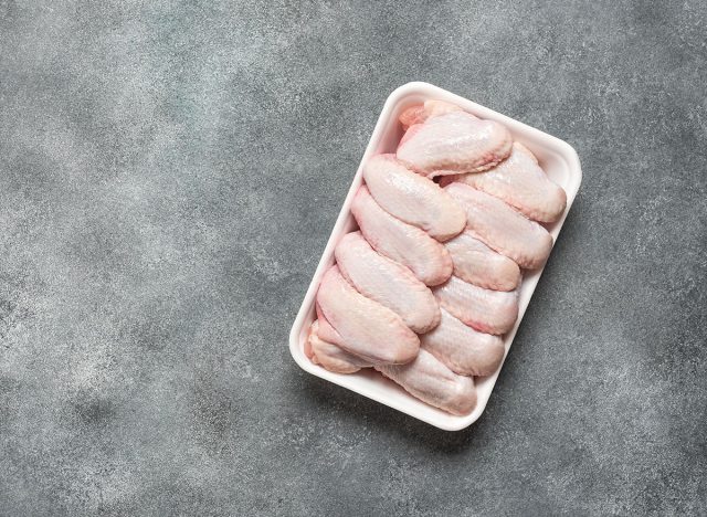 Raw chicken wings on tray, grey grunge background. Top view, flat lay, copy space