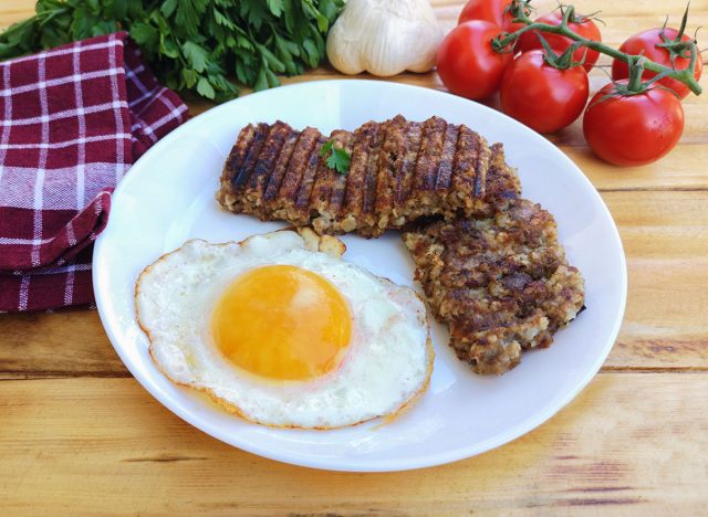 Breakfast with goetta and fried egg on plate (Cincinnati Breakfast Classic) on wooden table