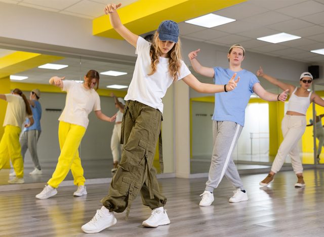 Teen girl in cap rehearses modern dances in dance hall