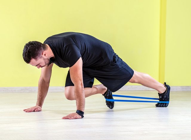 Guy working out with rubber band in studio gym.