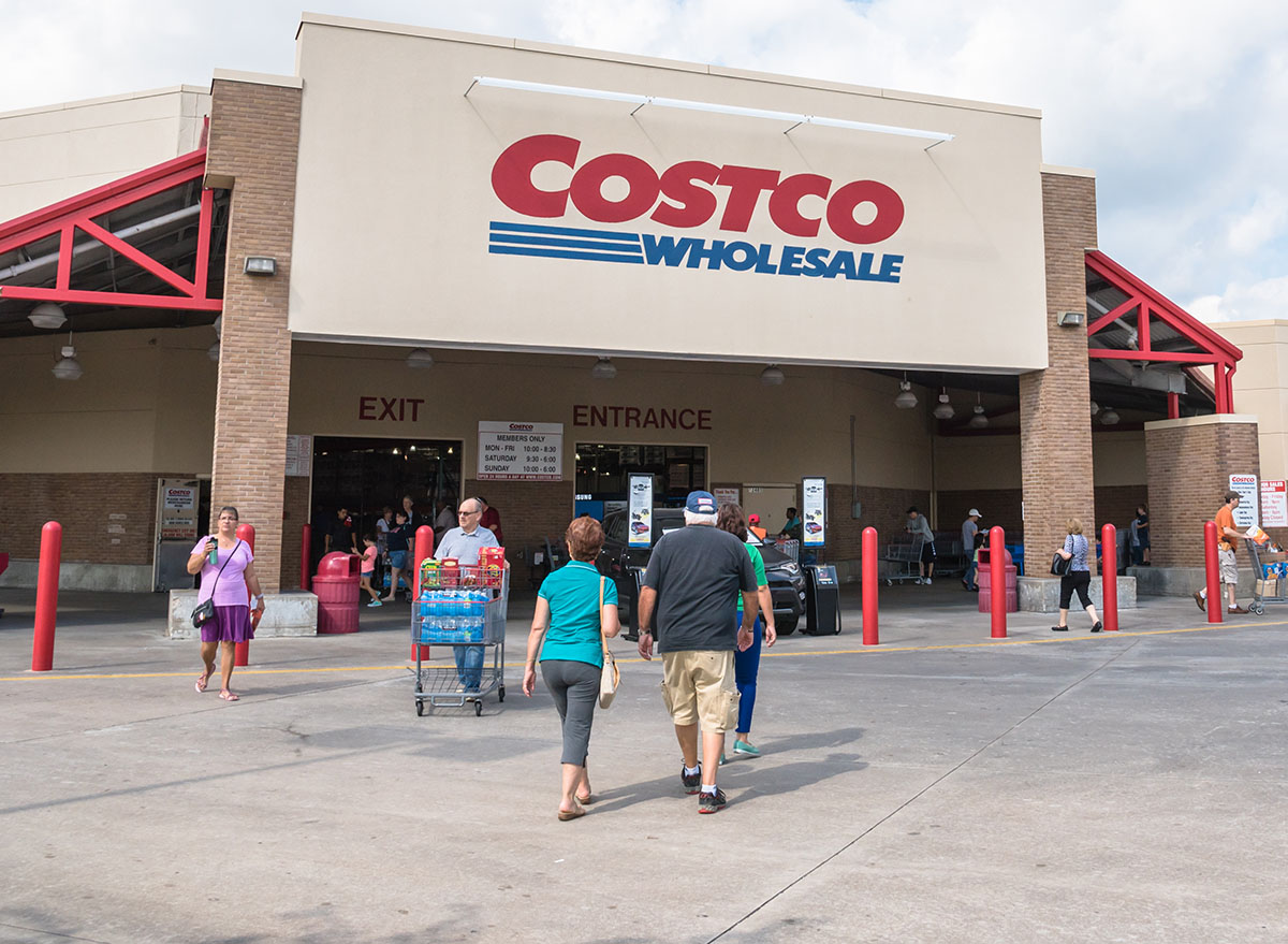 Customers walk in and exit at Costco entrance storefront. Costco Wholesale Corporation is largest membership-only warehouse club in US. It has 705 warehouses worldwide