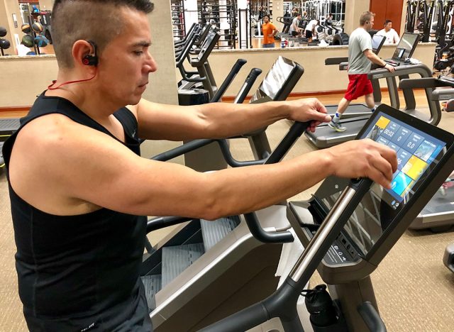 Gym equipment at Lifetime Fitness lined up on cardio area . Man exercising on stair master