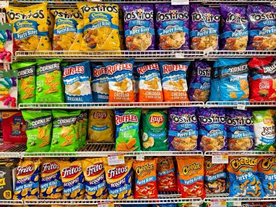 Florida - June 24, 2024: A wide assortment of potato chips and snacks from Frito-Lay displayed on shelves in a supermarket aisle, showcasing different flavors and brands.