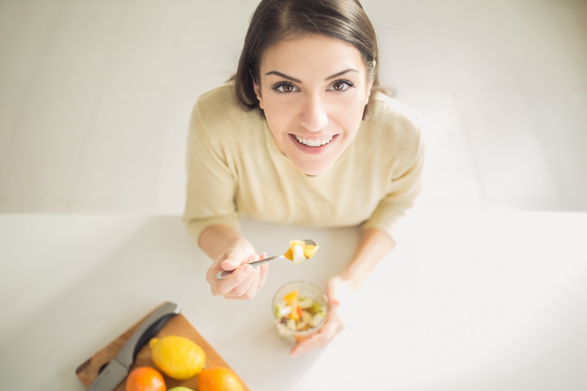 Healthy looking cheerful woman eating homemade organic fruit mix fruit salad.Fruit diet,dieting,nutrition,vegetarian concept.Food for beautiful skin,strong immune system,diet fitness meal.Heathy snack