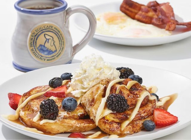 Another Broken Egg Cinnamon Roll French Toast next to a cup of coffee and eggs and bacon