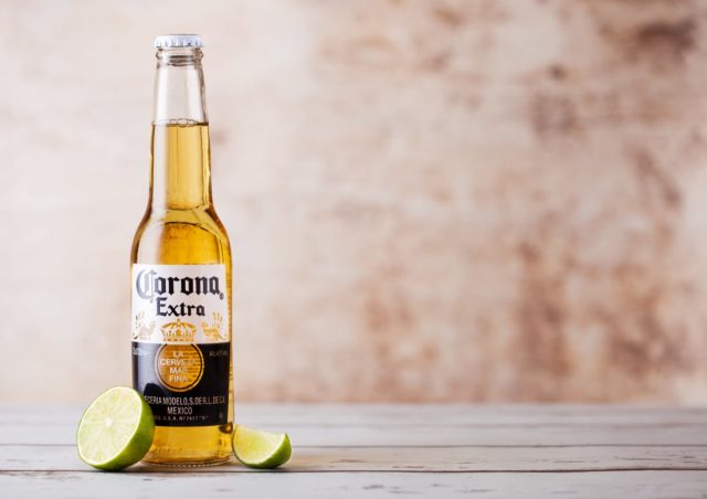 LONDON, UK - MARCH 10, 2018 : Bottles of Corona Extra Beer with lime slice on wooden background.Corona is the most popular imported beer in the US.