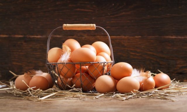 basket of fresh chicken eggs on a wooden background