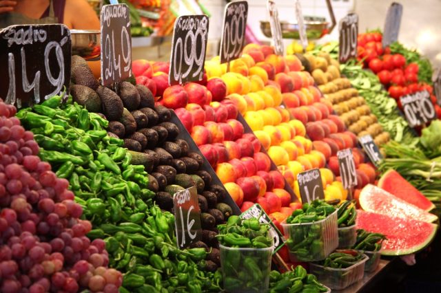 avocados and chilis stacked with other fruit on food market