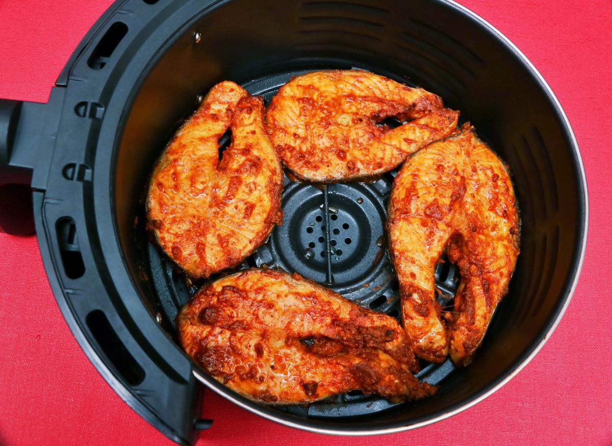 grilled delicious spicy salmon pieces on air fryer basket. Air fryer helps to cook foods without oils- Healthy cooking concept