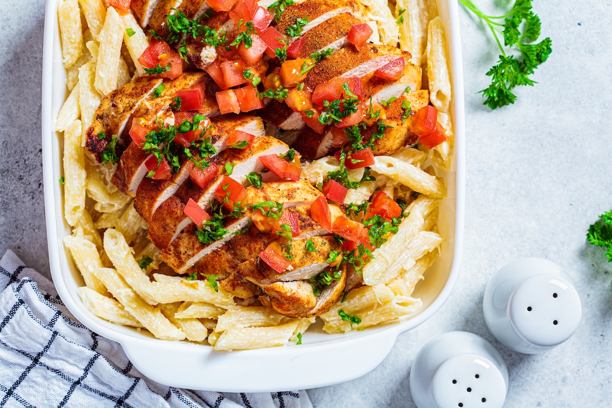 Cajun,Chicken,Pasta,With,Cheese,And,Tomato,In,White,Dish.