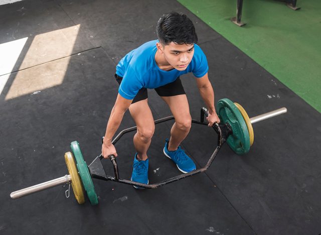 A young man mentally preparing himself for a set of trap bar deadlifts. Upper body workout session at an old hardcore gym.