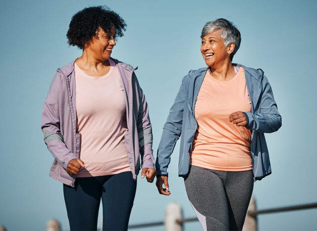 Fitness, exercise and senior women by ocean for healthy lifestyle, wellness and cardio on promenade. Sports, friends and female people in conversation on boardwalk for walking, training and workout