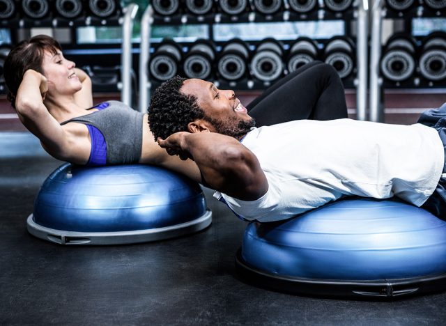 Fit couple doing bosu ball exercises at gym