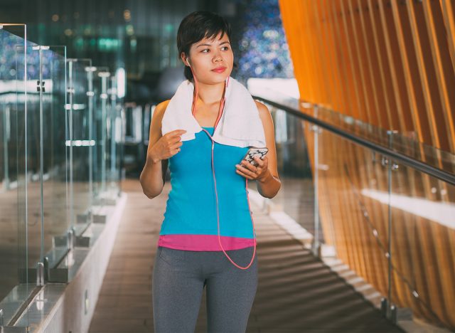 Sportswoman Listening to Music in Gym Hall, walking 