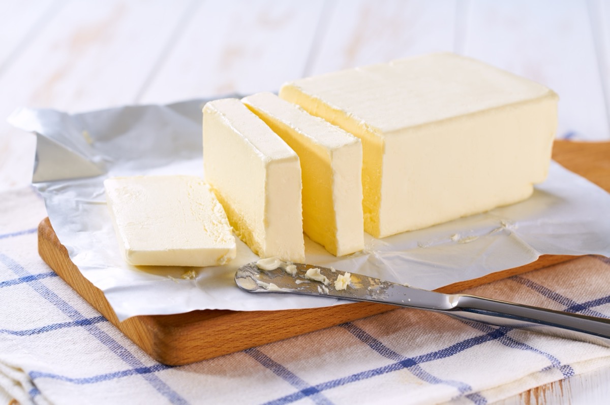 Tasty butter and knife on a kitchen table, selective focus.