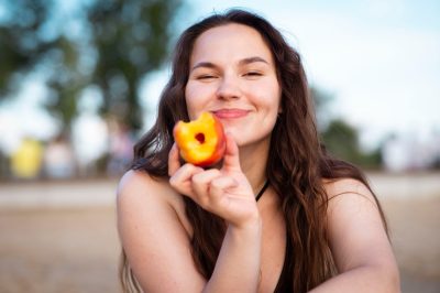 Girl eats juicy peach on the beach. Ripe peach.